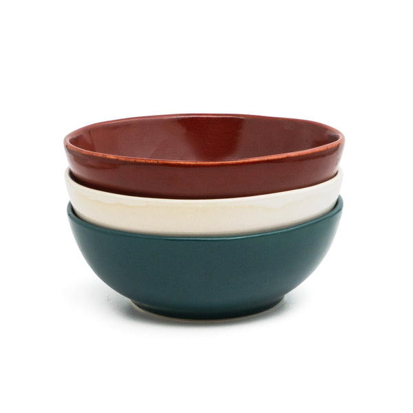 Üç el yapımı stoneware bowl üst üste: bordo, krem ve koyu yeşil
