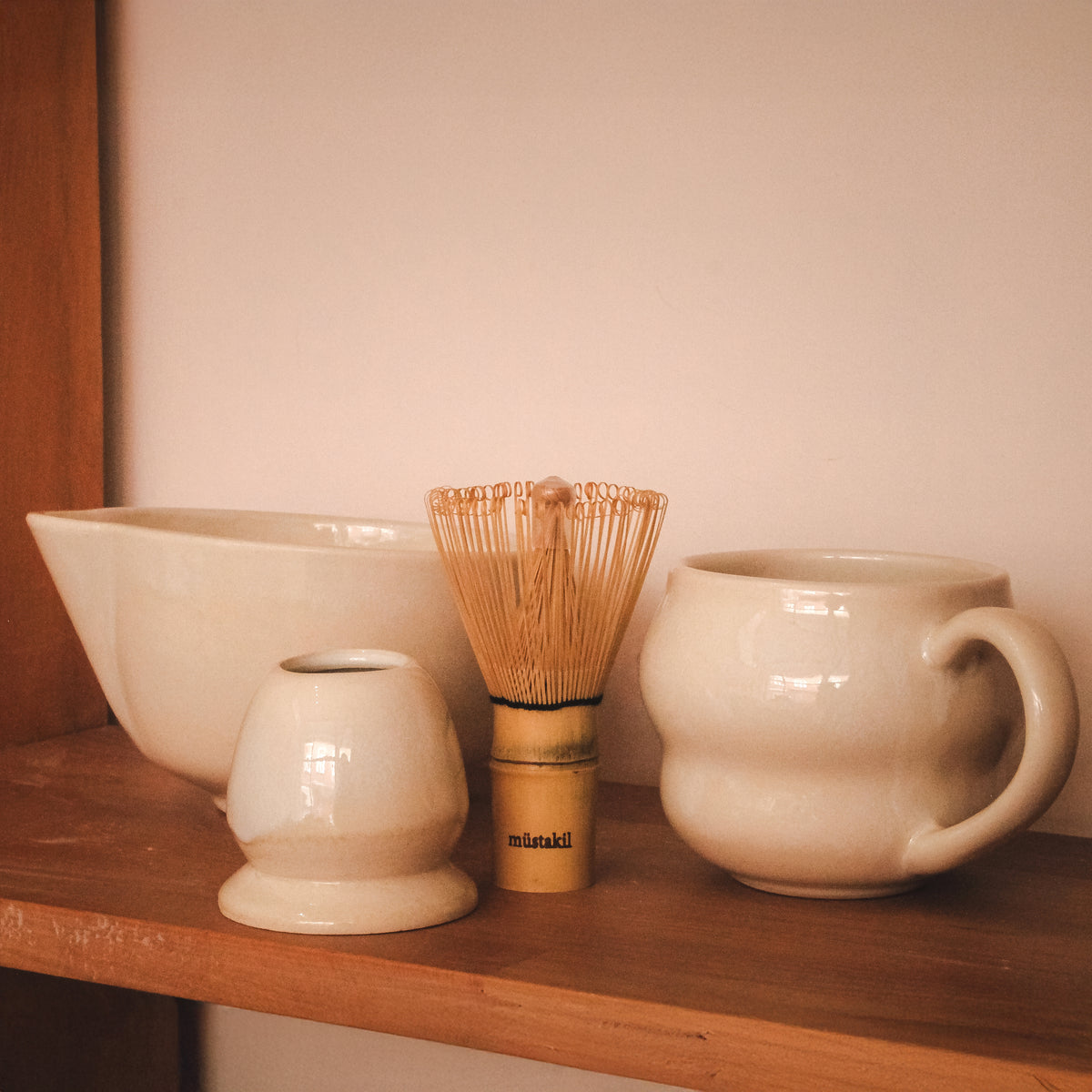 Ahşap rafta bambu whisk, stoneware kupa ve sürahi