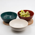 Üç stoneware bowl ahşap tabla üzerinde, içlerinde üzüm