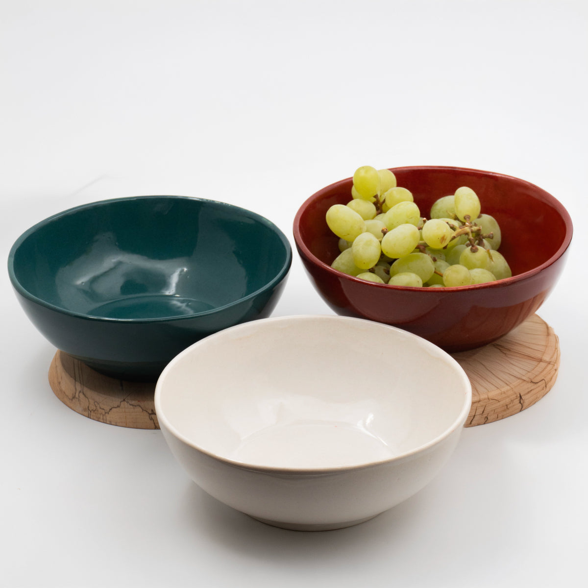Üç stoneware bowl ahşap tabla üzerinde, içlerinde üzüm