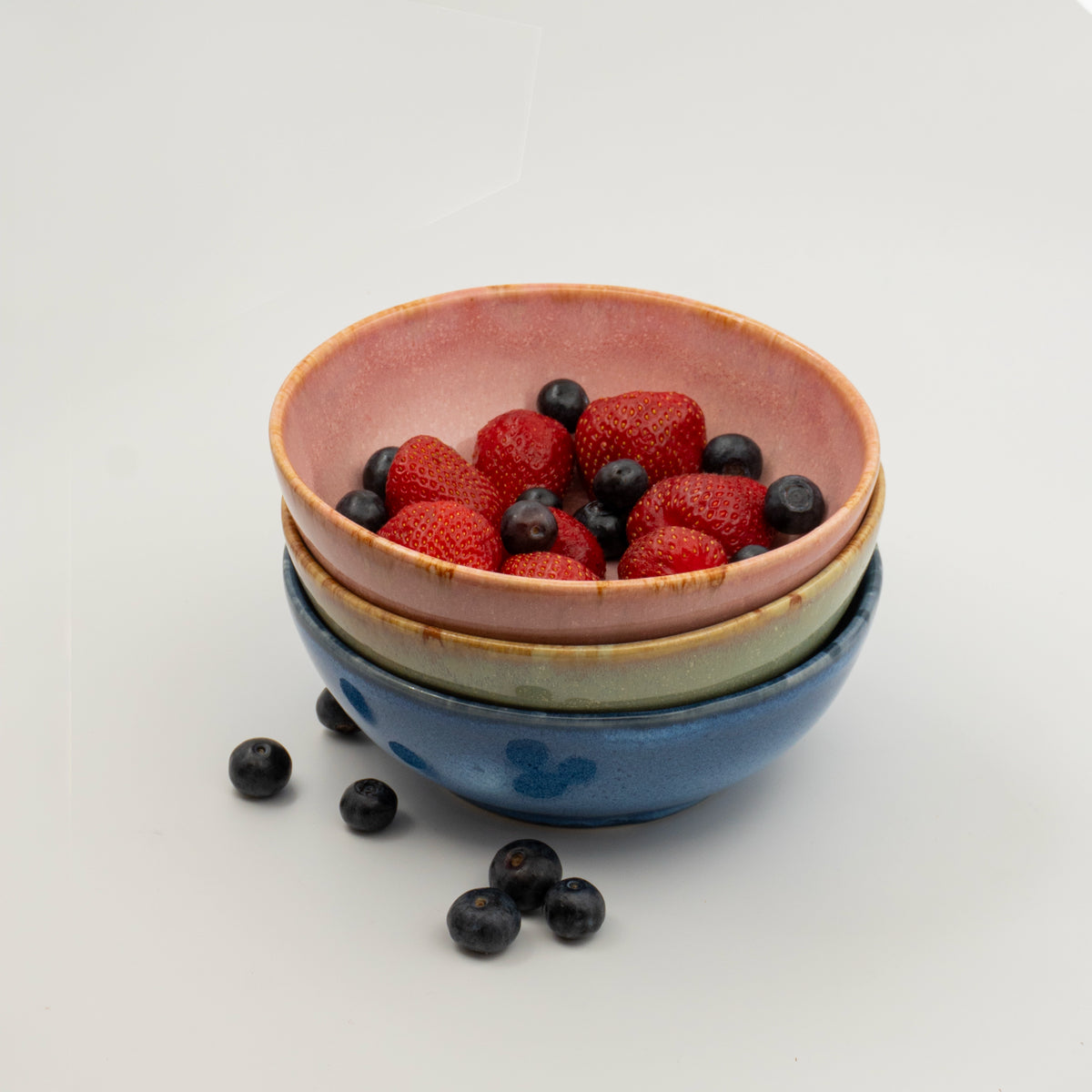Üst üste dizilmiş üç stoneware bowl, üstünde böğürtlen ve çilek