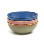 Üç el yapımı stoneware bowl üst üste: mavi, pembe ve yeşil