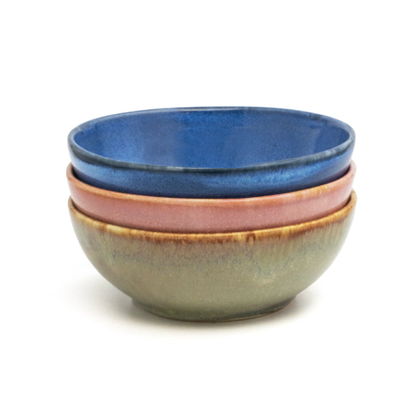 Üç el yapımı stoneware bowl üst üste: mavi, pembe ve yeşil